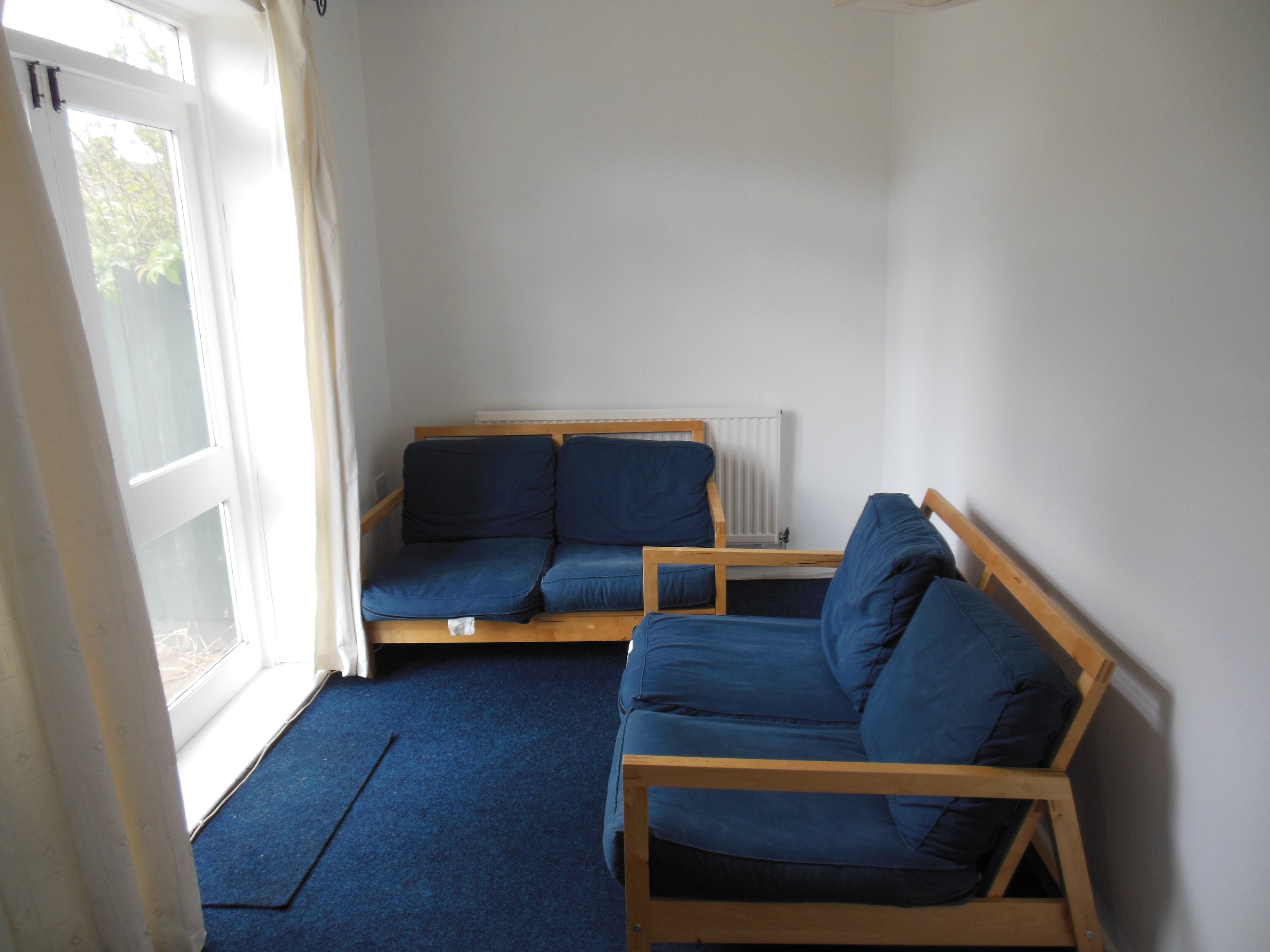 Lounge area with blue fabric seating and a blue carpet. Patio doors.