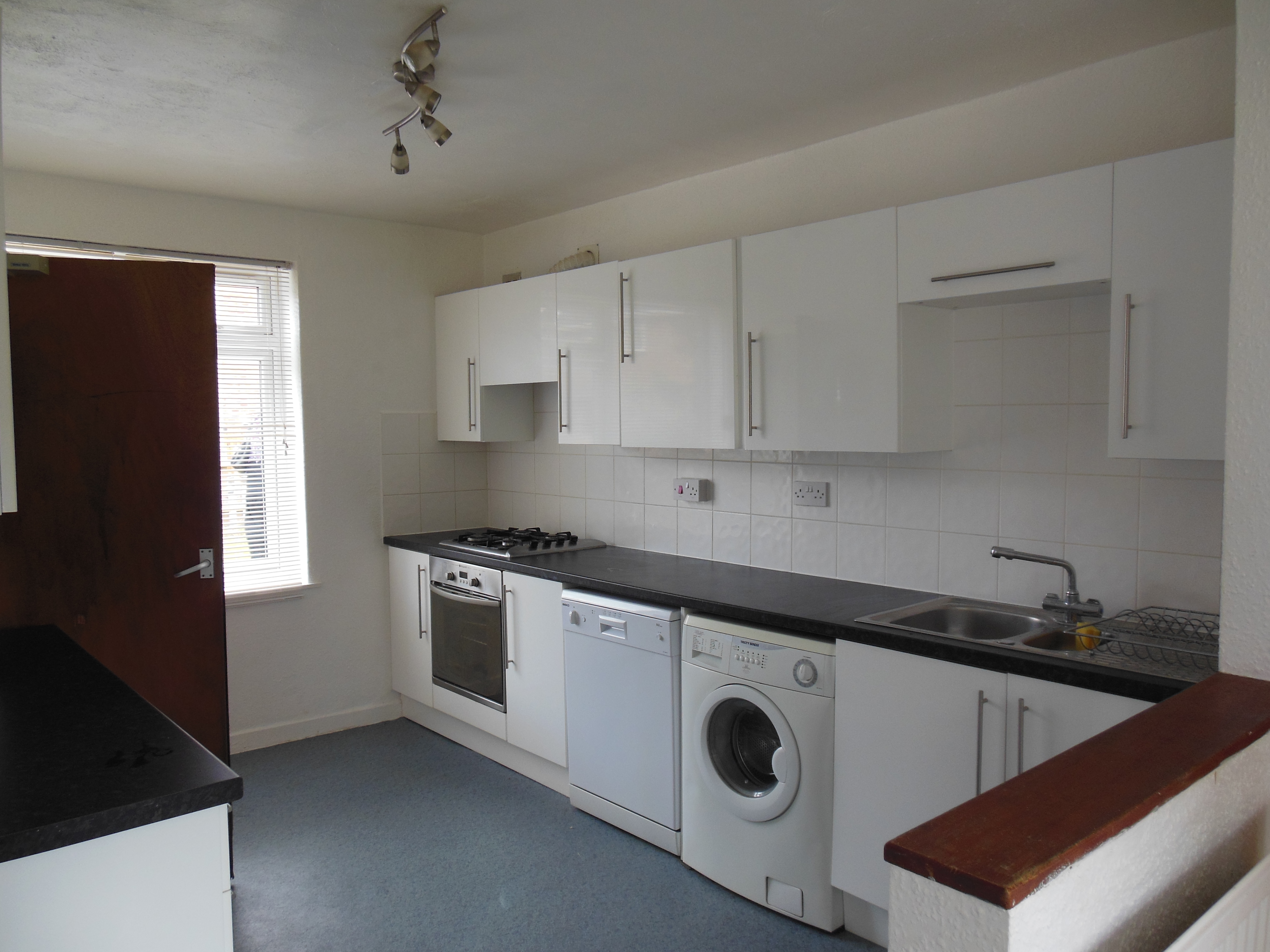 Large kitchen with white fitted units, under the counter washing machine, oven/hob and fridge freezer.