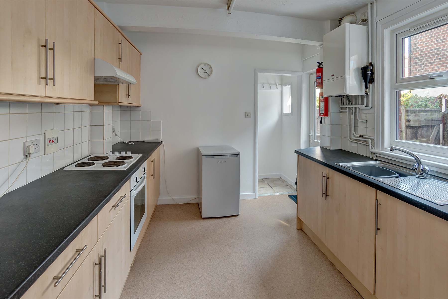 Spacious galley kitchen with light cabinets and black worktop