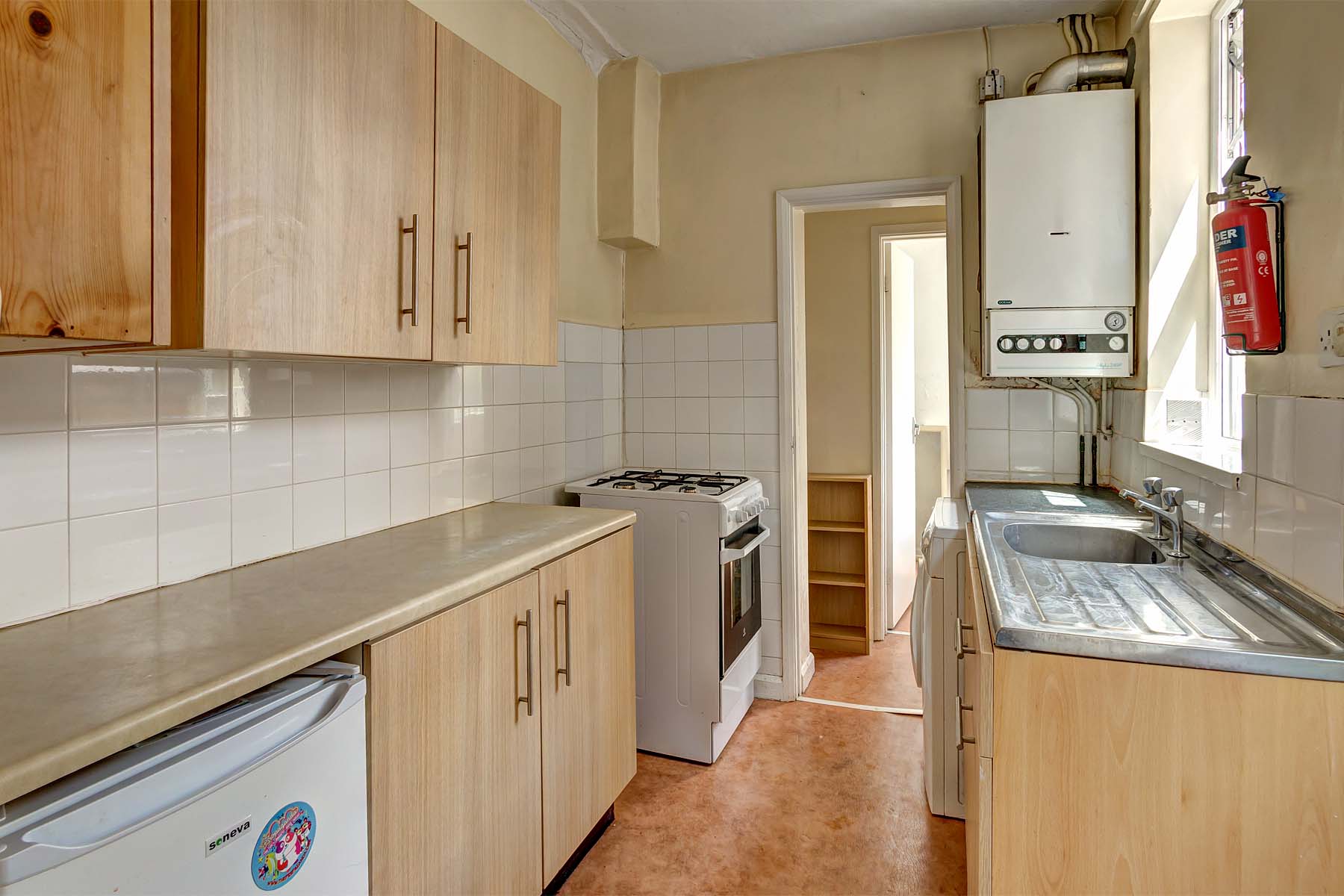 Galley style kitchen with wood effect fitted units and a light grain coloured worktop.