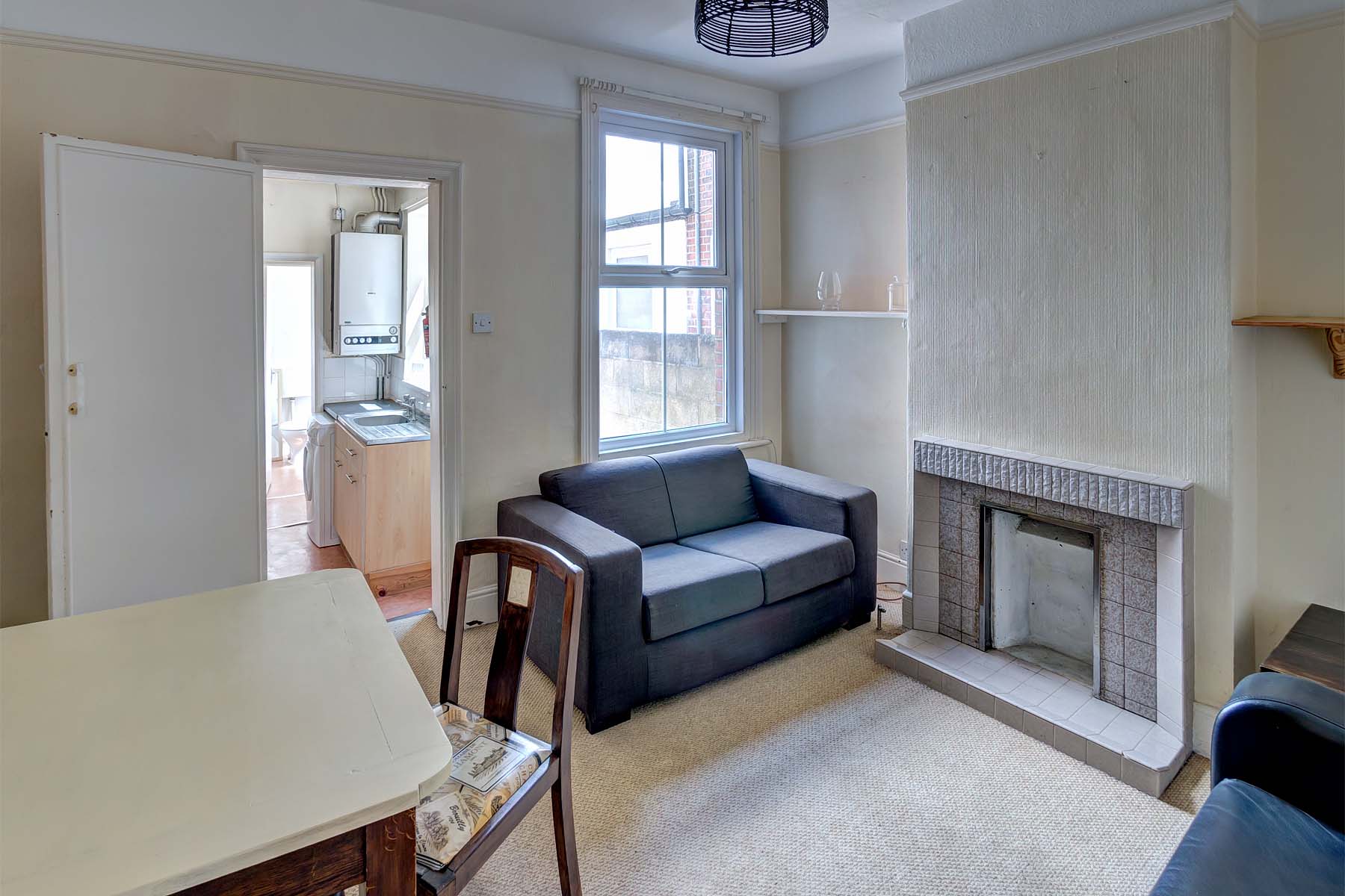 Lounge area with two black leather sofas and a wooden dining table. Decorative fireplace and shelving on each side of the wall.