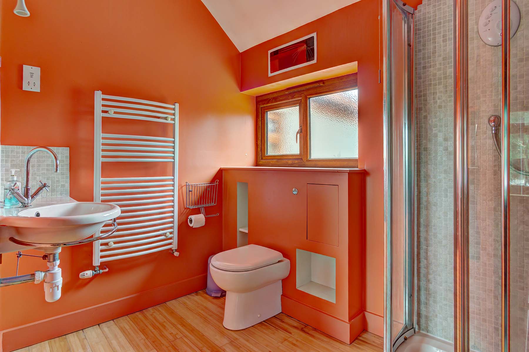 Bathroom with orange walls, toilet, and towel warmer