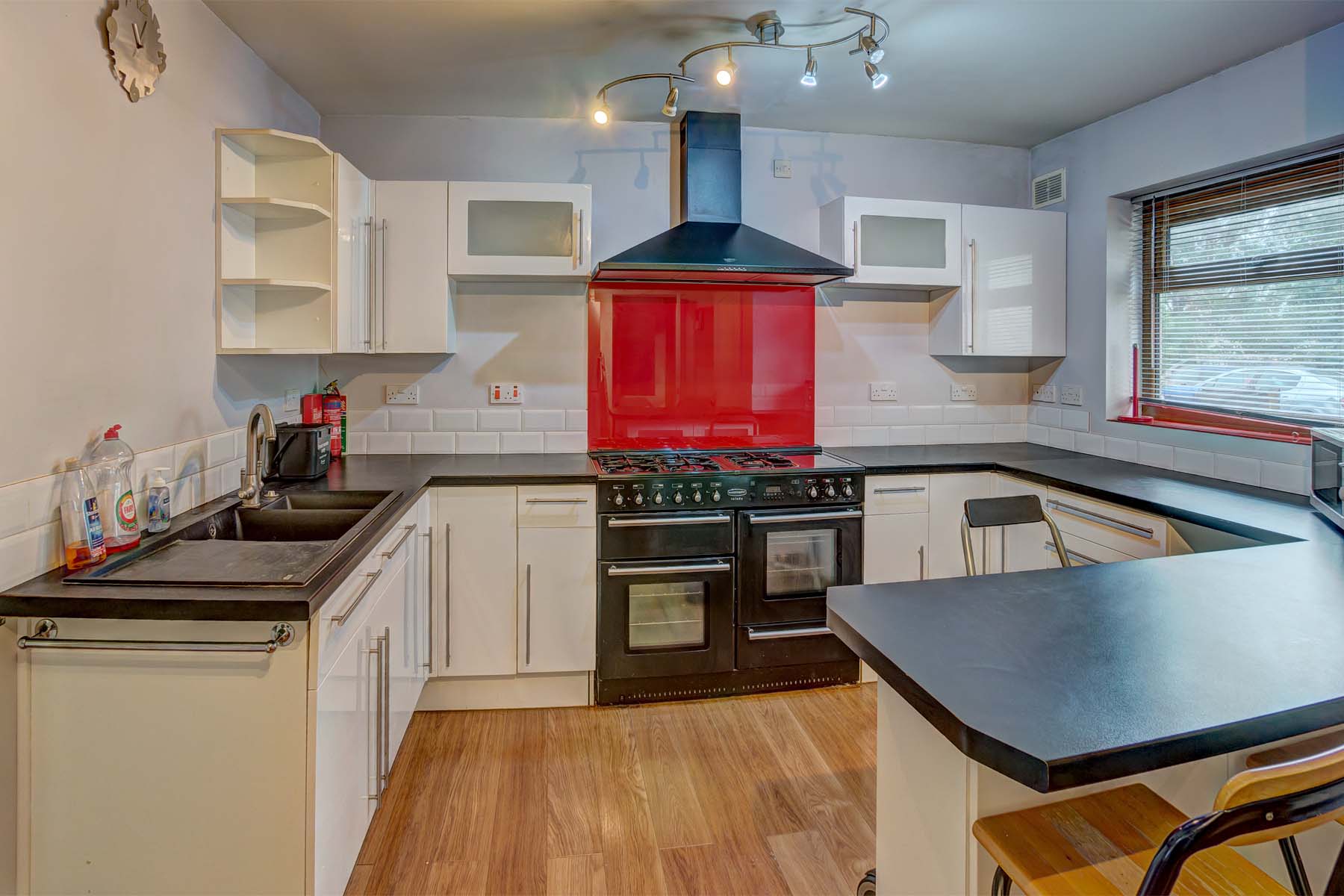 Kitchen with black range style cooker, white units, and black worktops