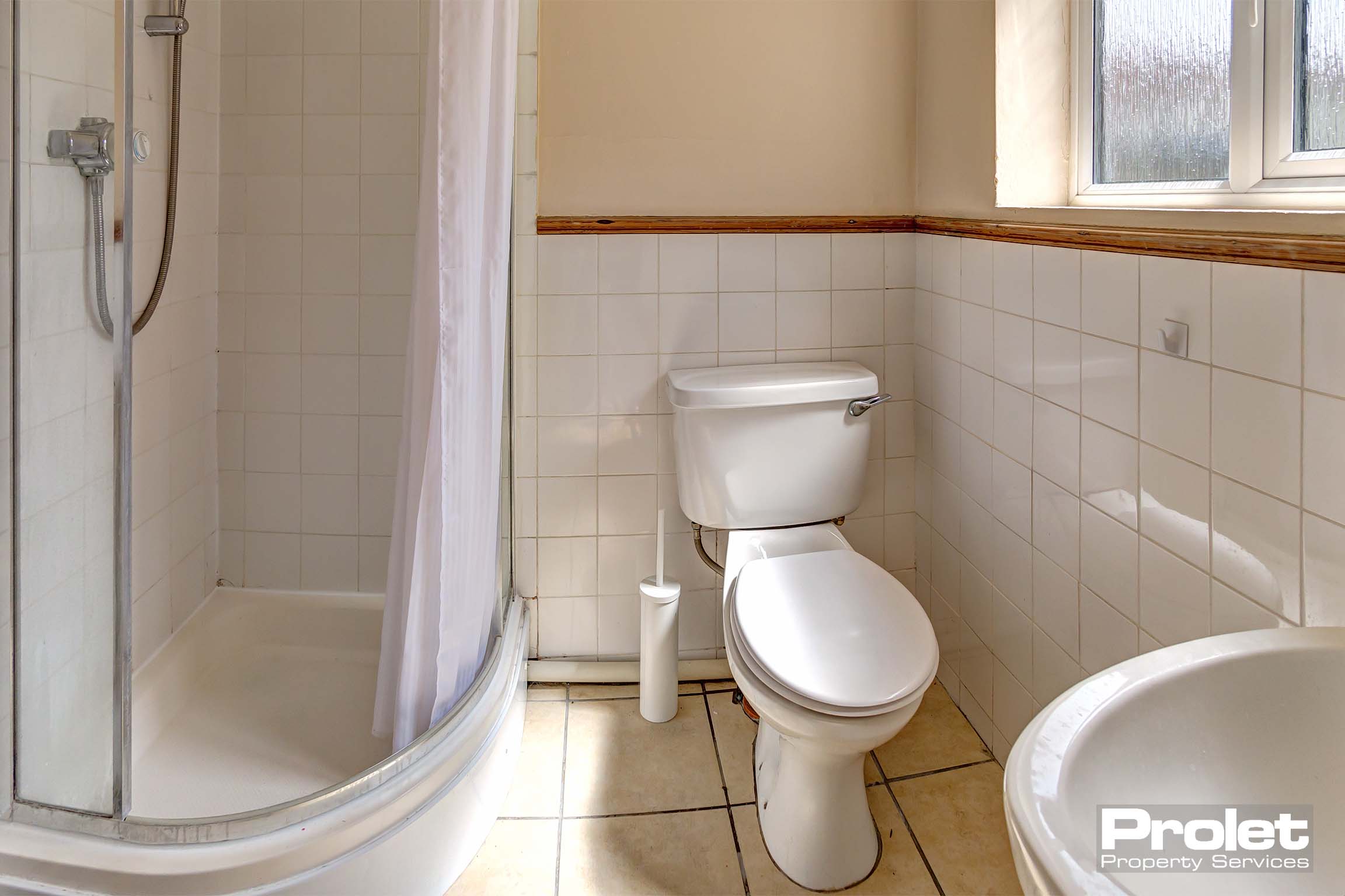 Bathroom with curved shower cubicle, toilet, and sink