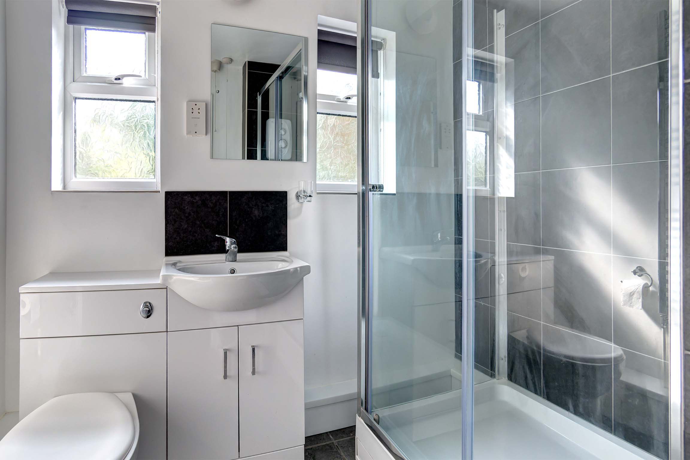 Modern bathroom with a glass walk in shower and a toilet and sink unit.