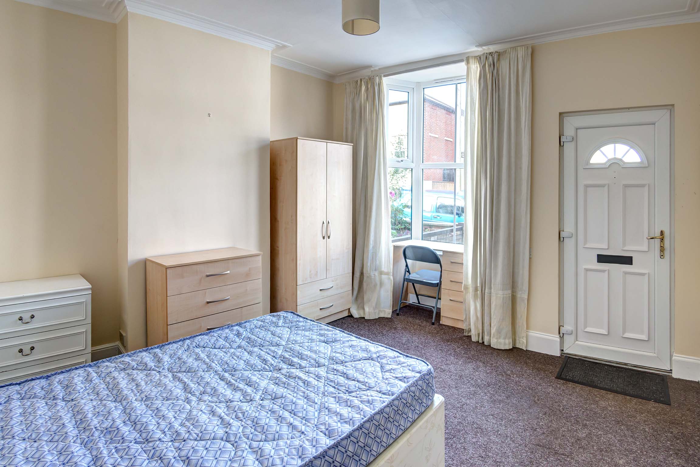 Front bedroom with divan bed and wooden wardrobe and chest of drawers, desk near the window.