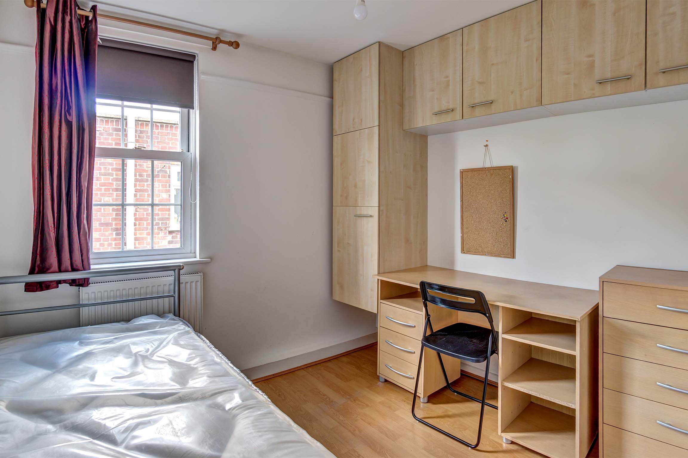 Bedroom with built in wooden storage cupboards and desk.