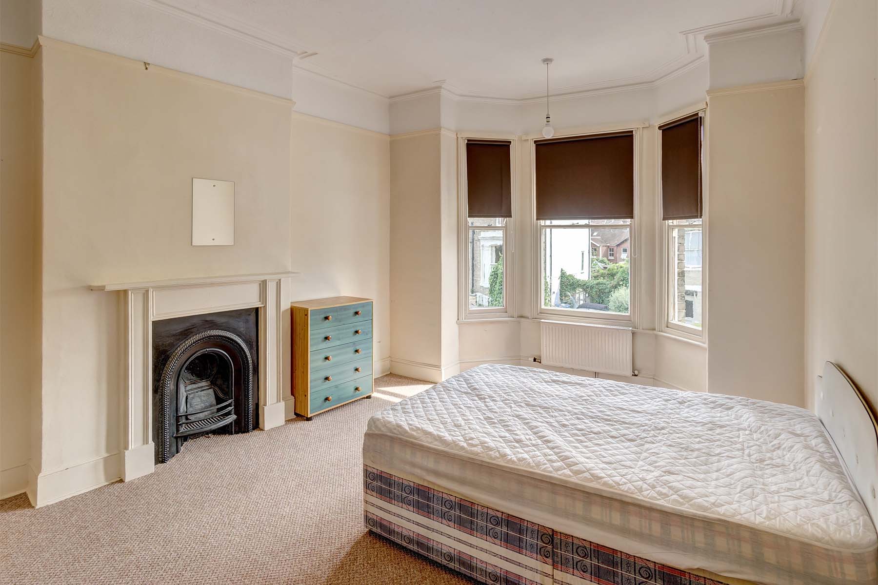 Large double bedroom with divan bed, chest of drawers and a decorative fireplace.