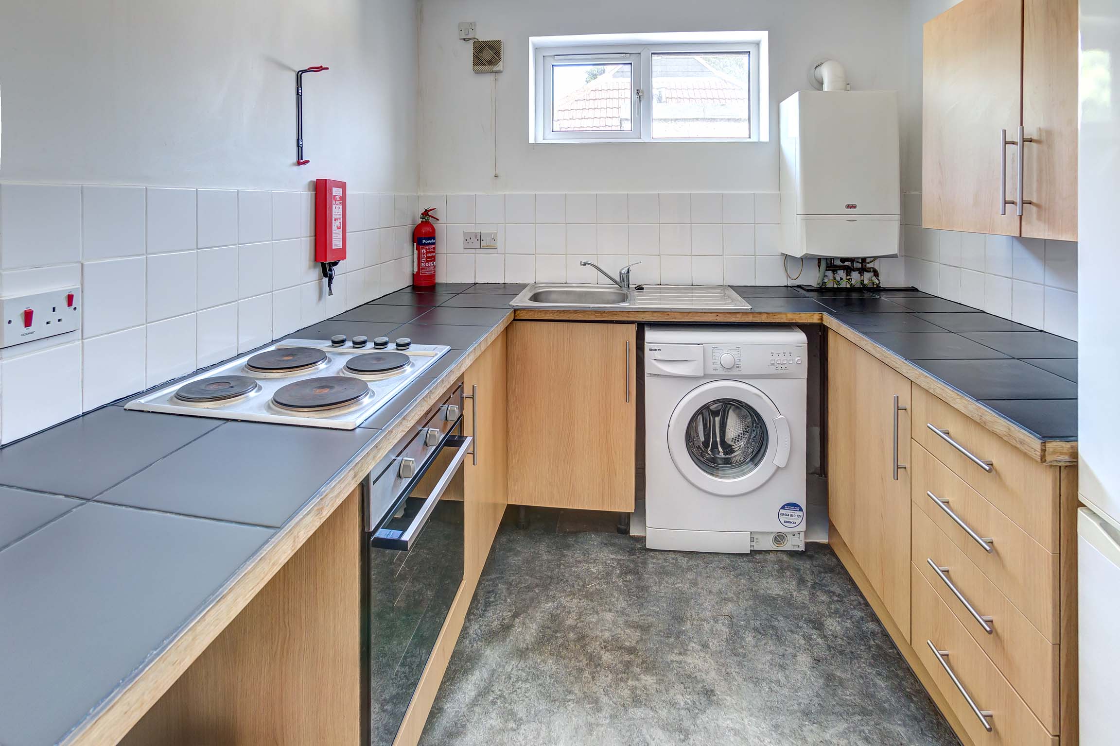 Kitchen with wood effect cabinets, black worktops, and white goods.