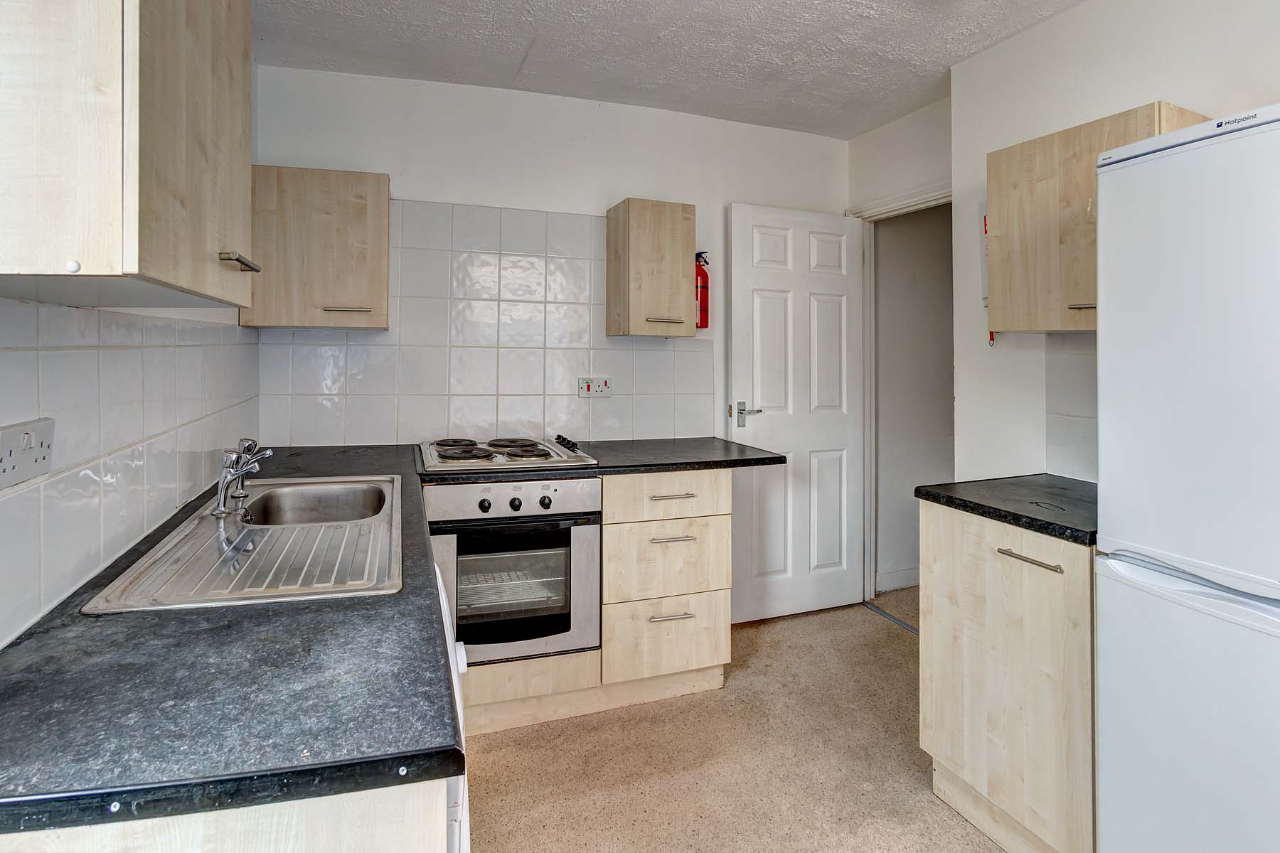 Light wood effect fitted kitchen with black worktop