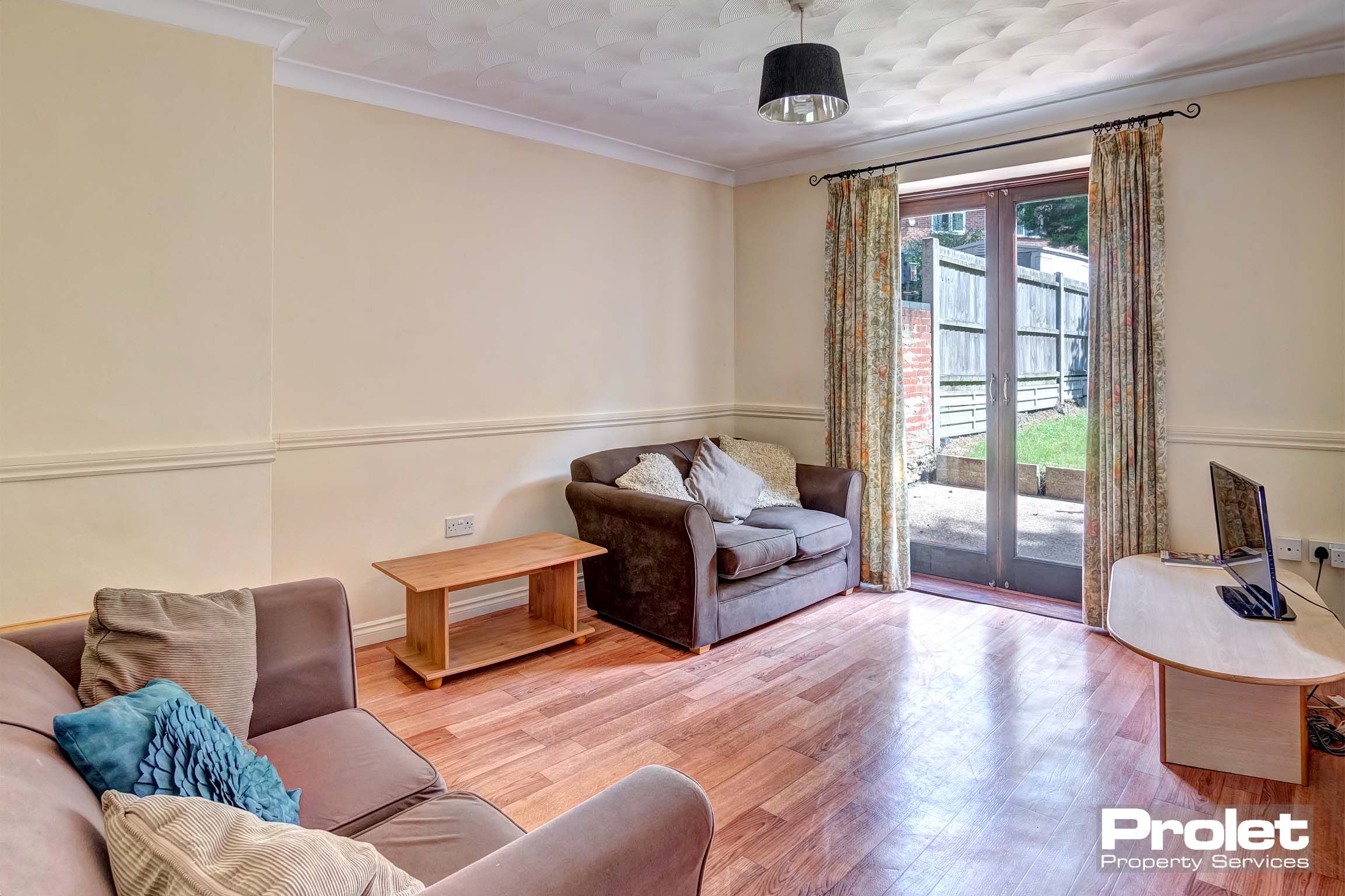 Lounge area with two fabric sofas, a wooden side table with wooden flooring.