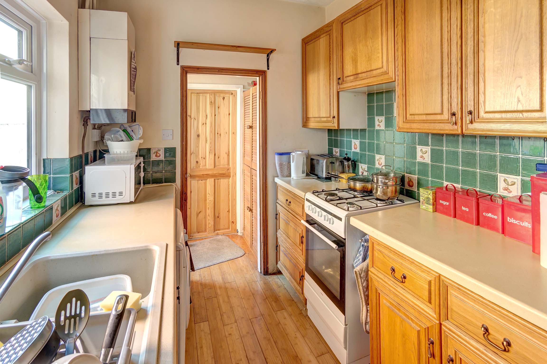 Galley style kitchen with wooden cabinets and white goods