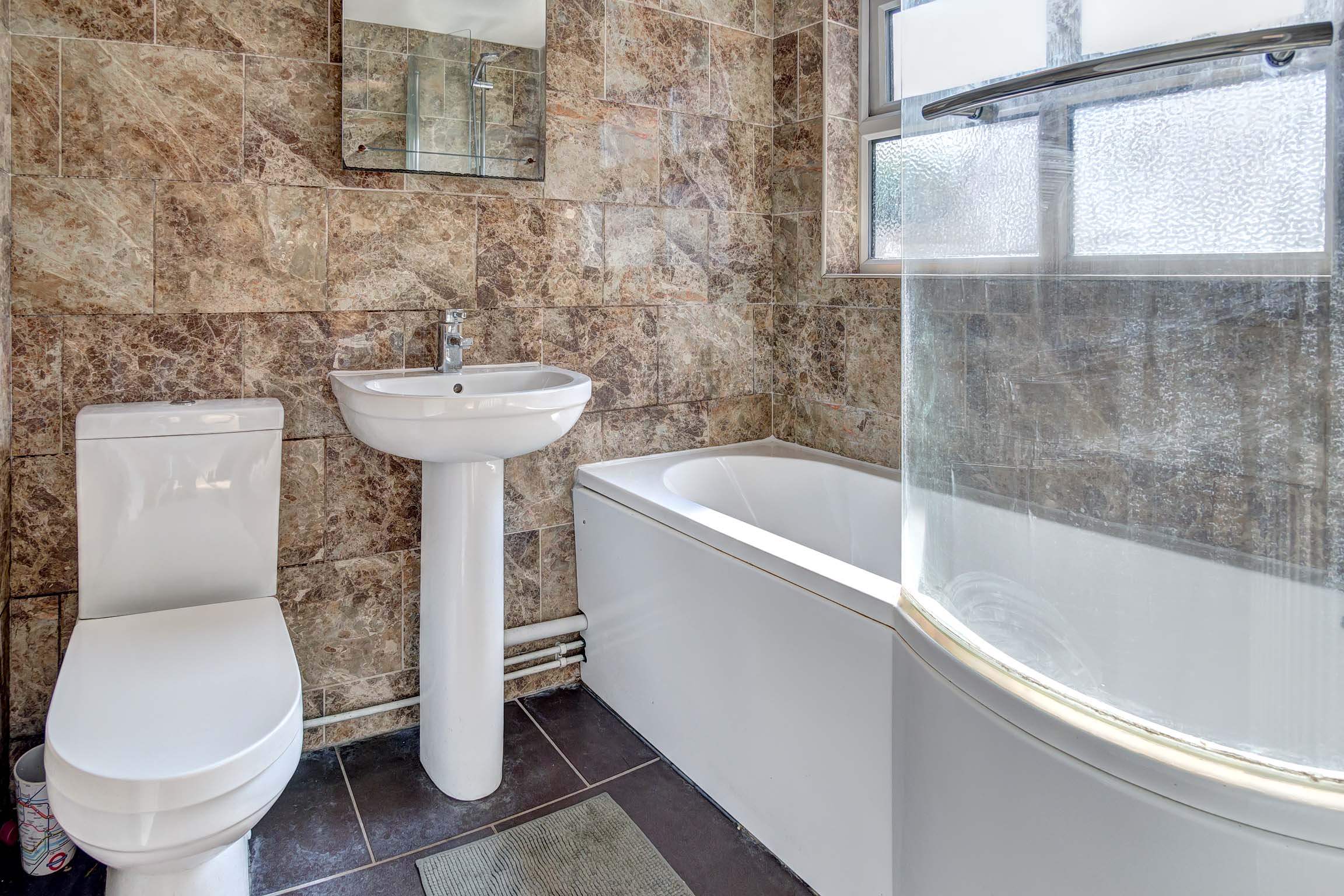 Bathroom with large shower over bath, toilet, and sink