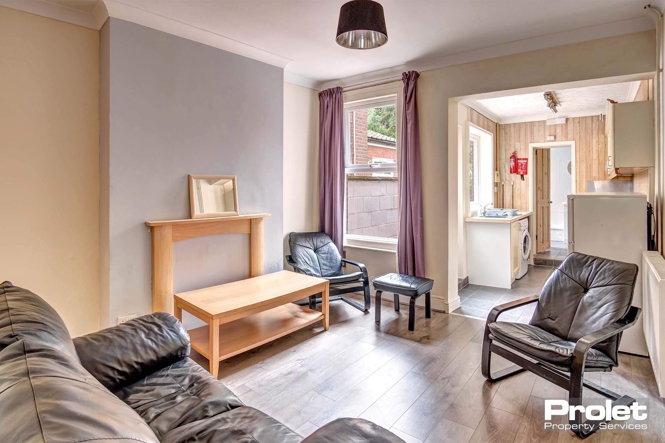 Living room with sofas and coffee table leading to kitchen