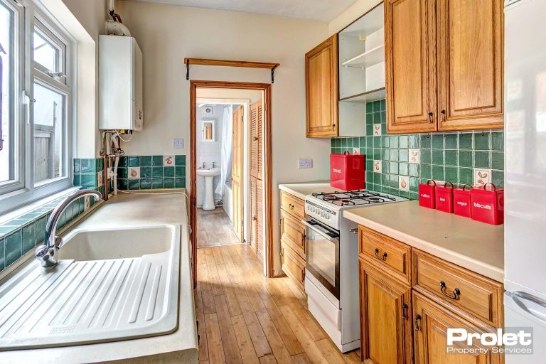 Galley style kitchen with wooden cabinets and white goods