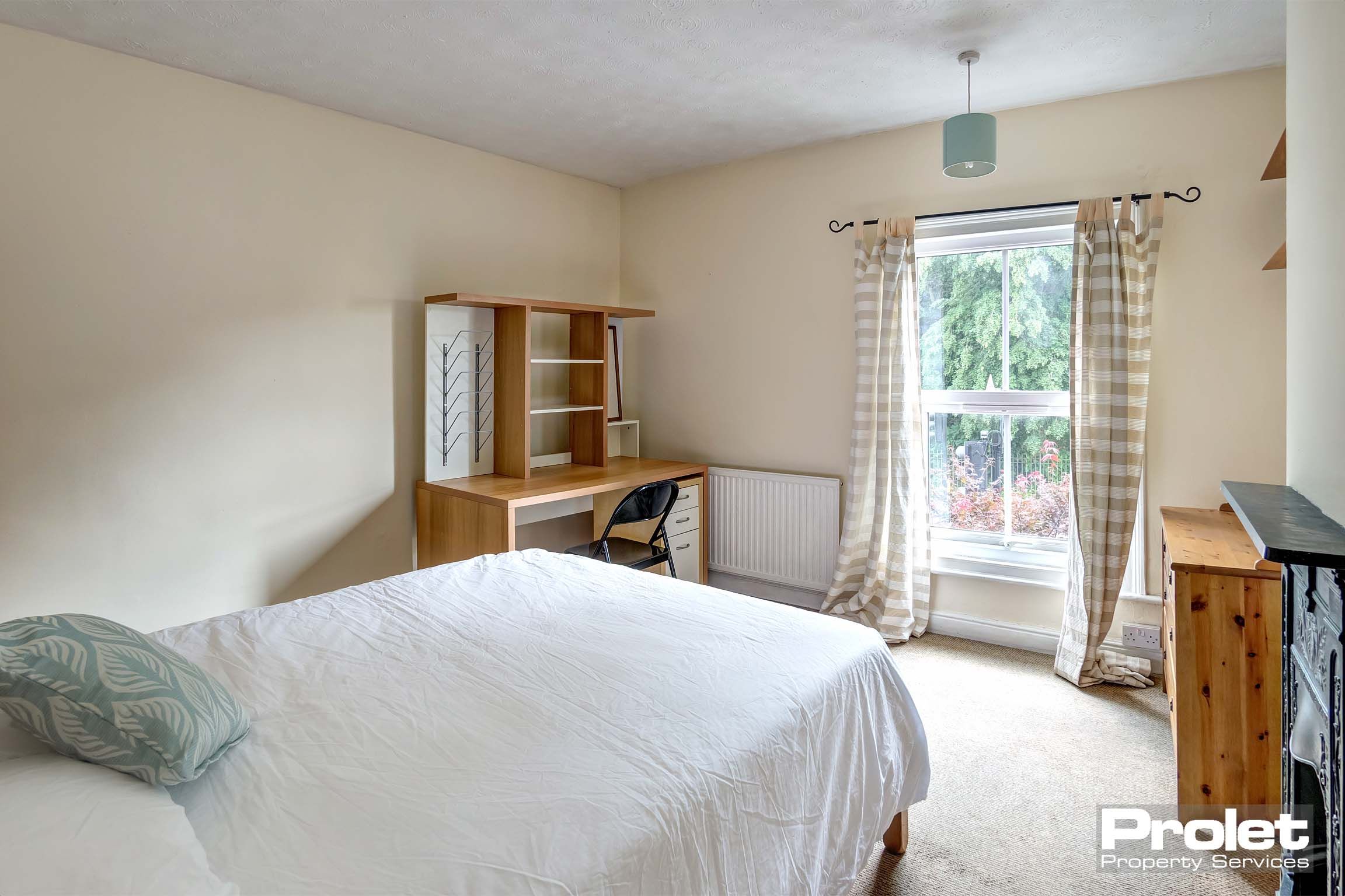 Bedroom with double bed, wooden furnishings, and cream walls