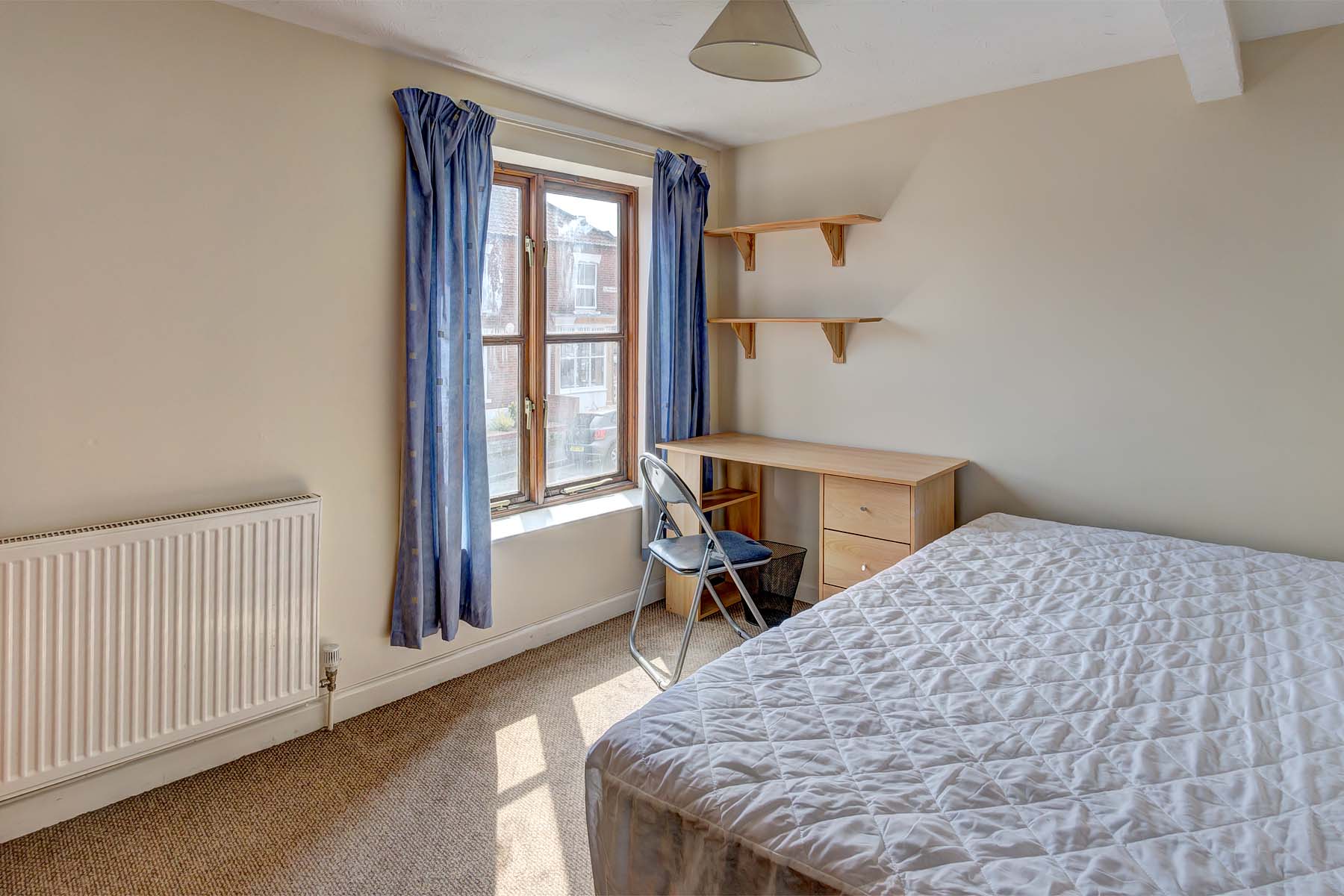 Bedroom with double bed, shelves, and desk.