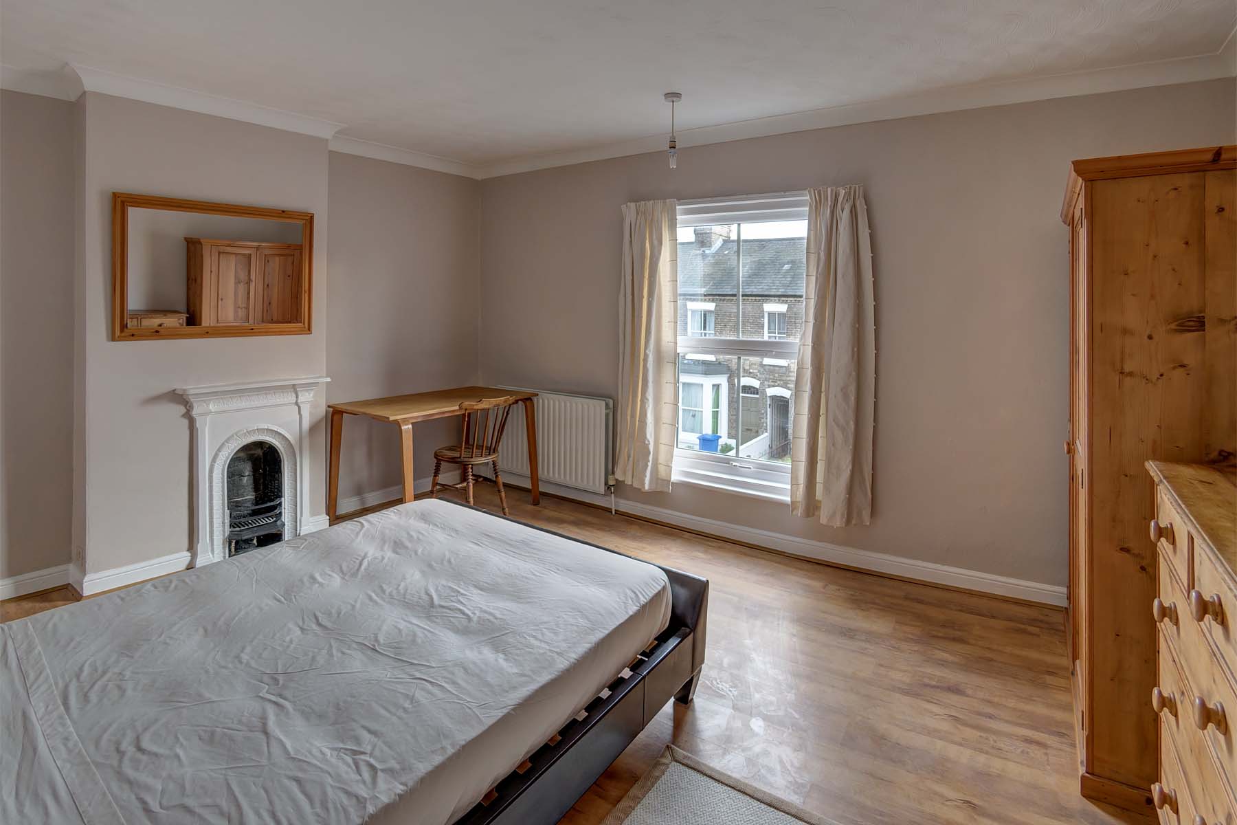 Large bedroom with wood floors, double bed, period fireplace, and desk