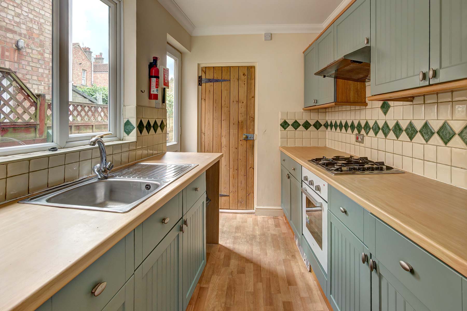 Galley kitchen with laminate flooring, light green cabinets, and wood effect worktops