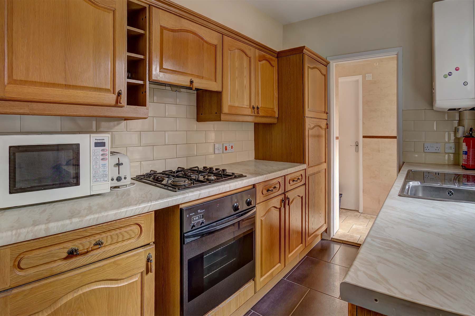 Galley kitchen with wooden cabinets and gas cooker