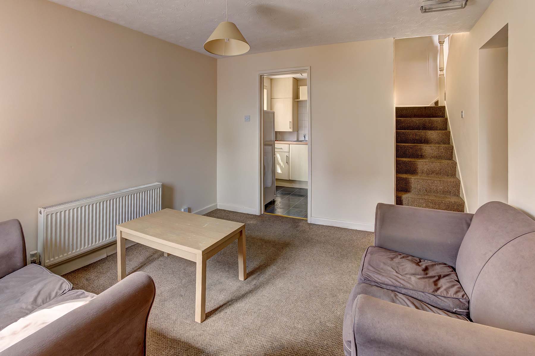 Living room with sofas and coffee table, leading to kitchen