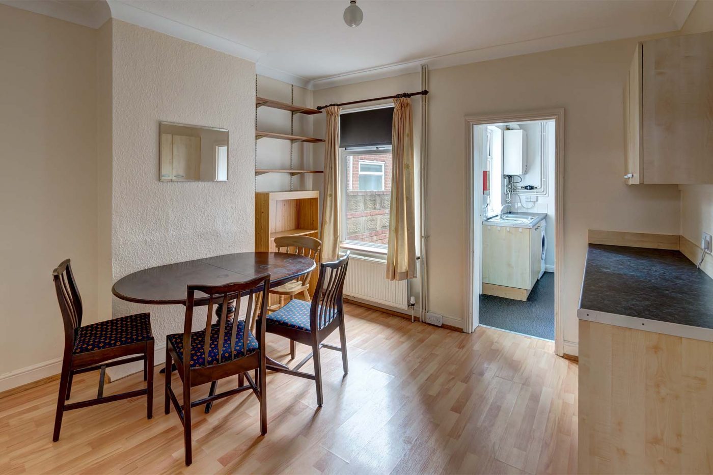 Dining room with dining set, shelving, and cabinets, leading to kitchen