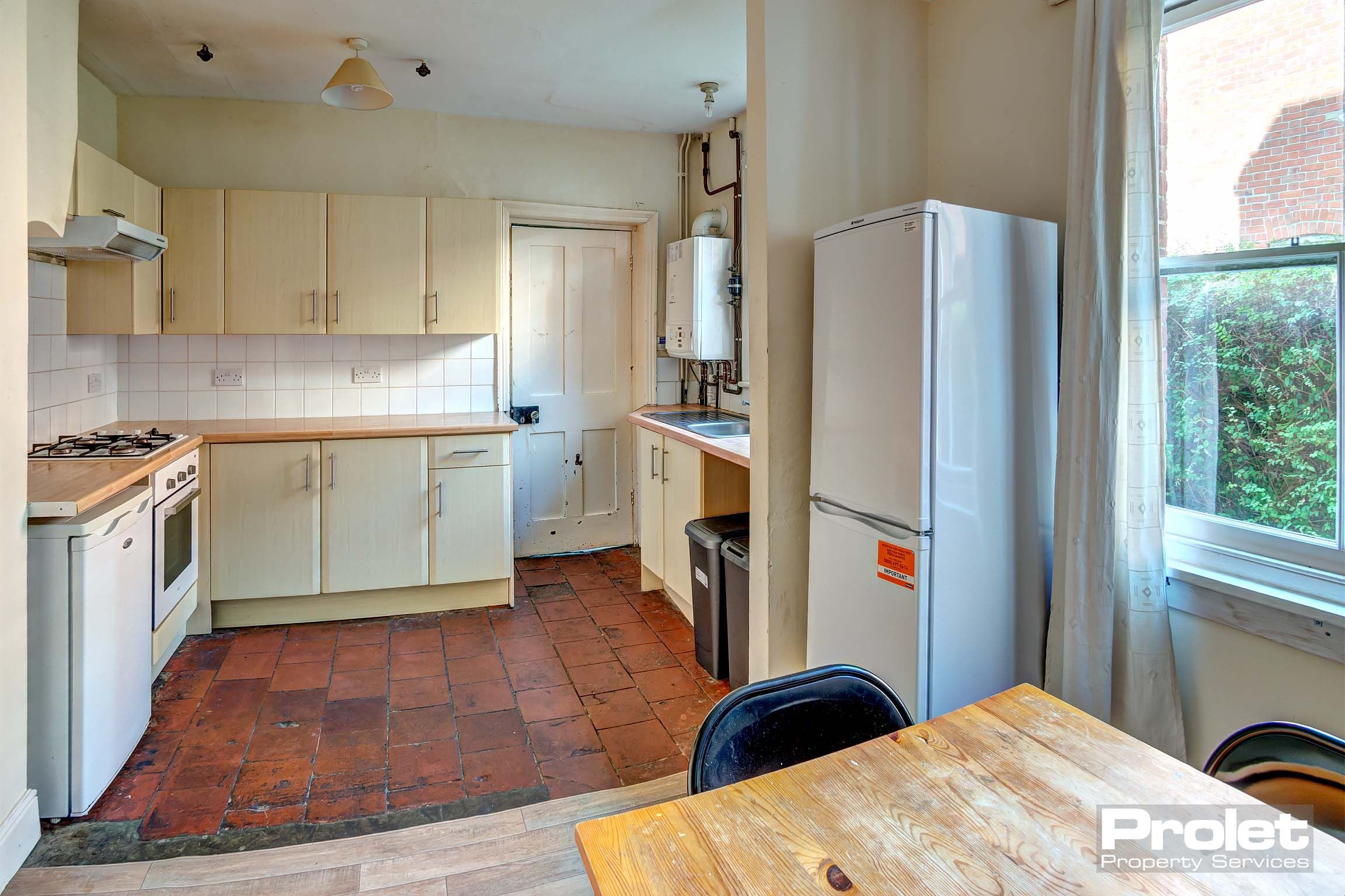 Large kitchen with tiled floor, dining table, and white goods