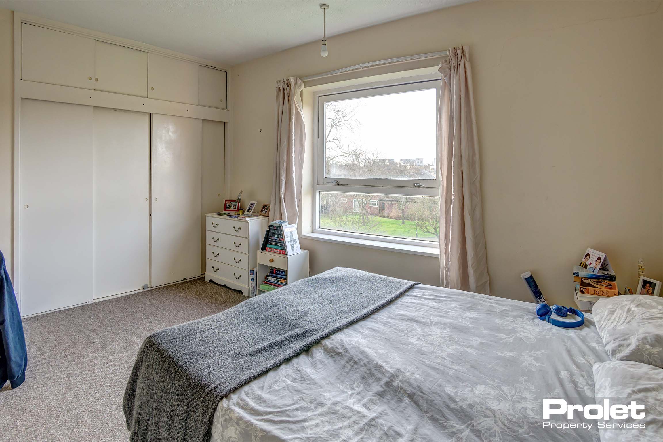 Double bedroom with large built in wardrobes, a white chest of drawers and a double bed and mattress.