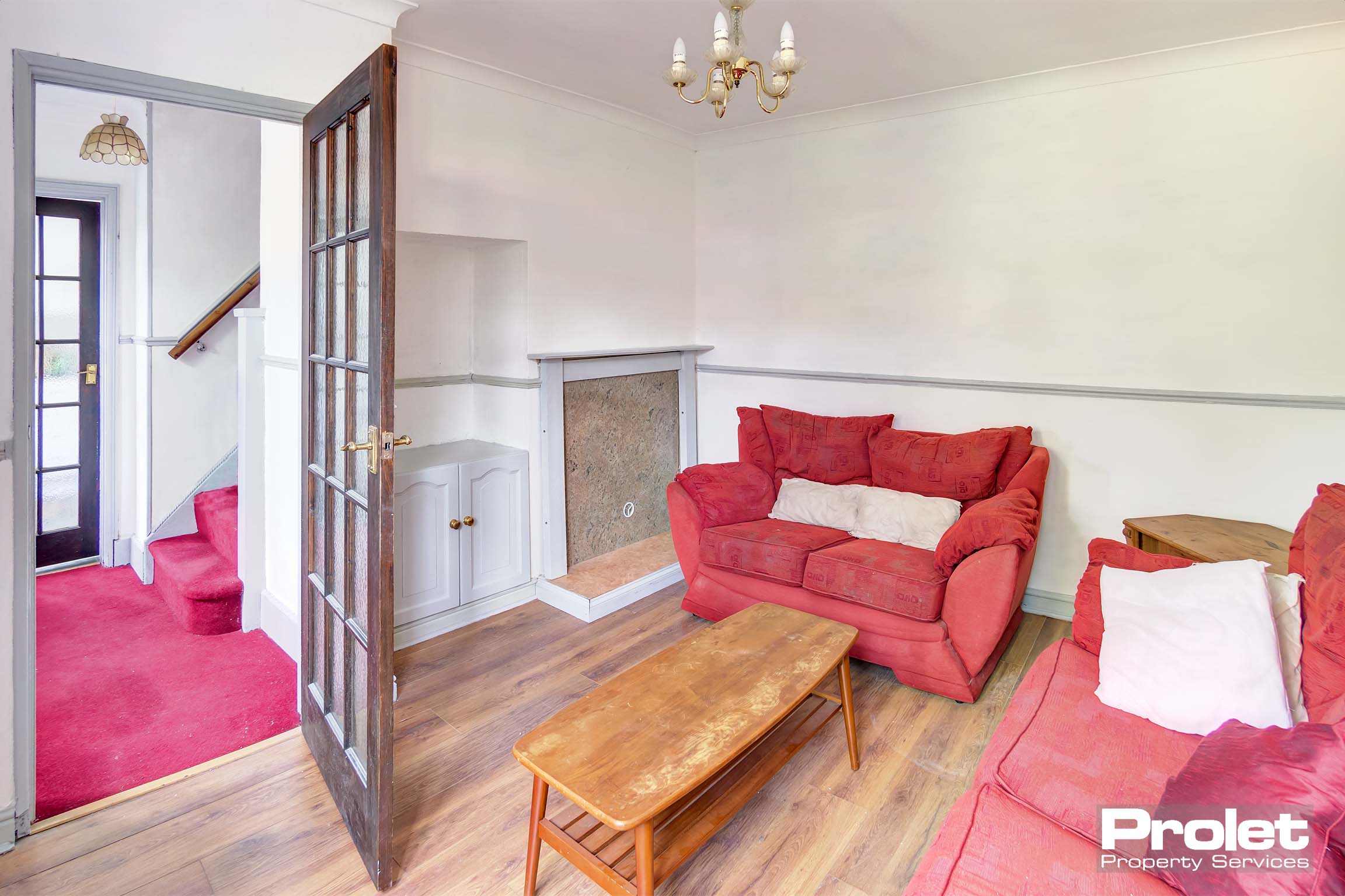 Lounge area with wooden effect flooring and two red fabric sofas with a coffee table.