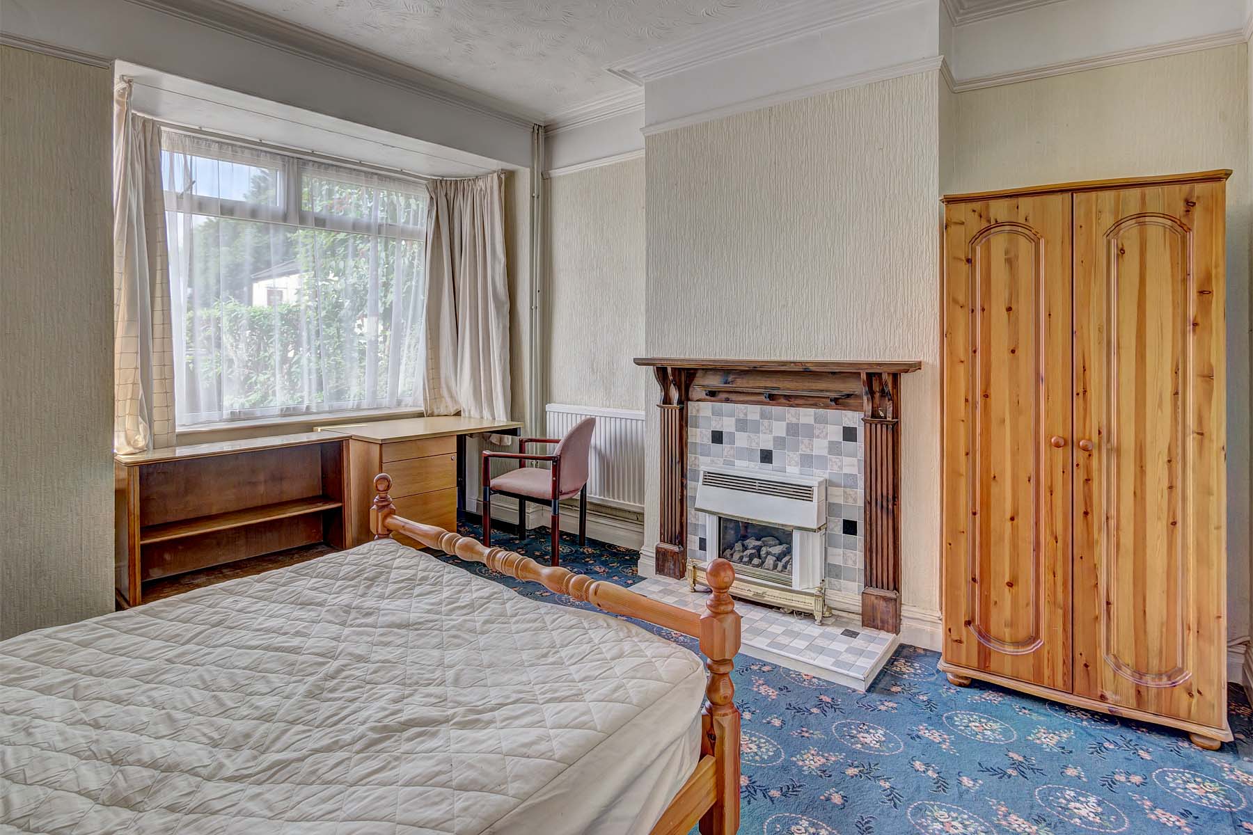 Large bedroom with double bed, blue carpet, and wooden furnishings