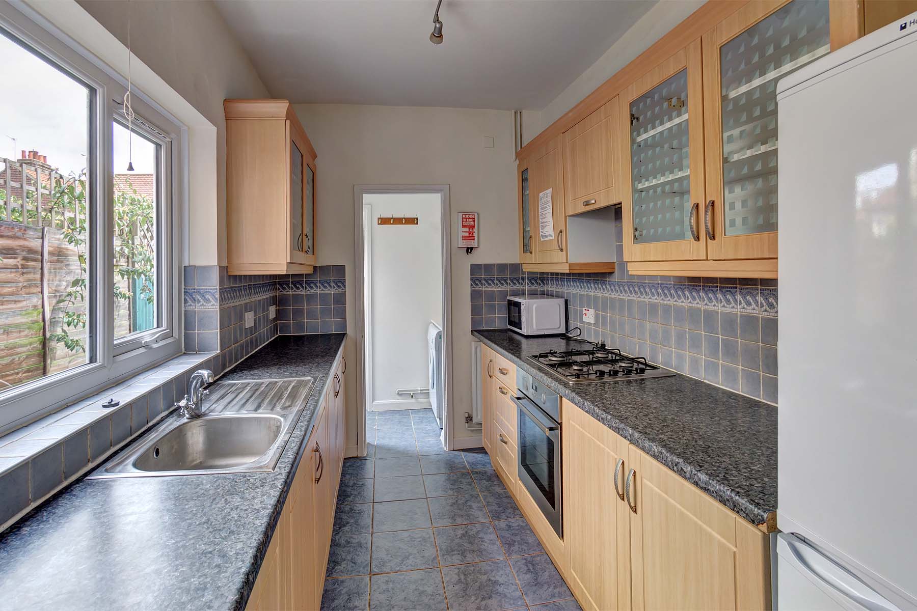 Galey kitchen with wood effect cabinets, black worktops, and white goods