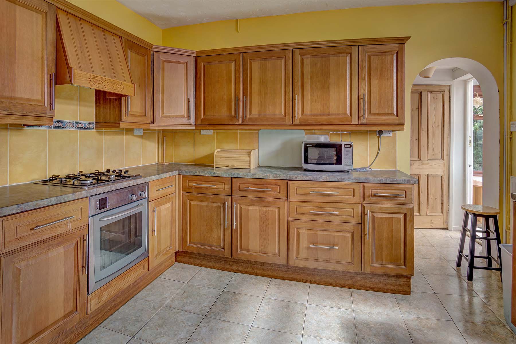 Large kitchen with wooden cabinets, and white goods