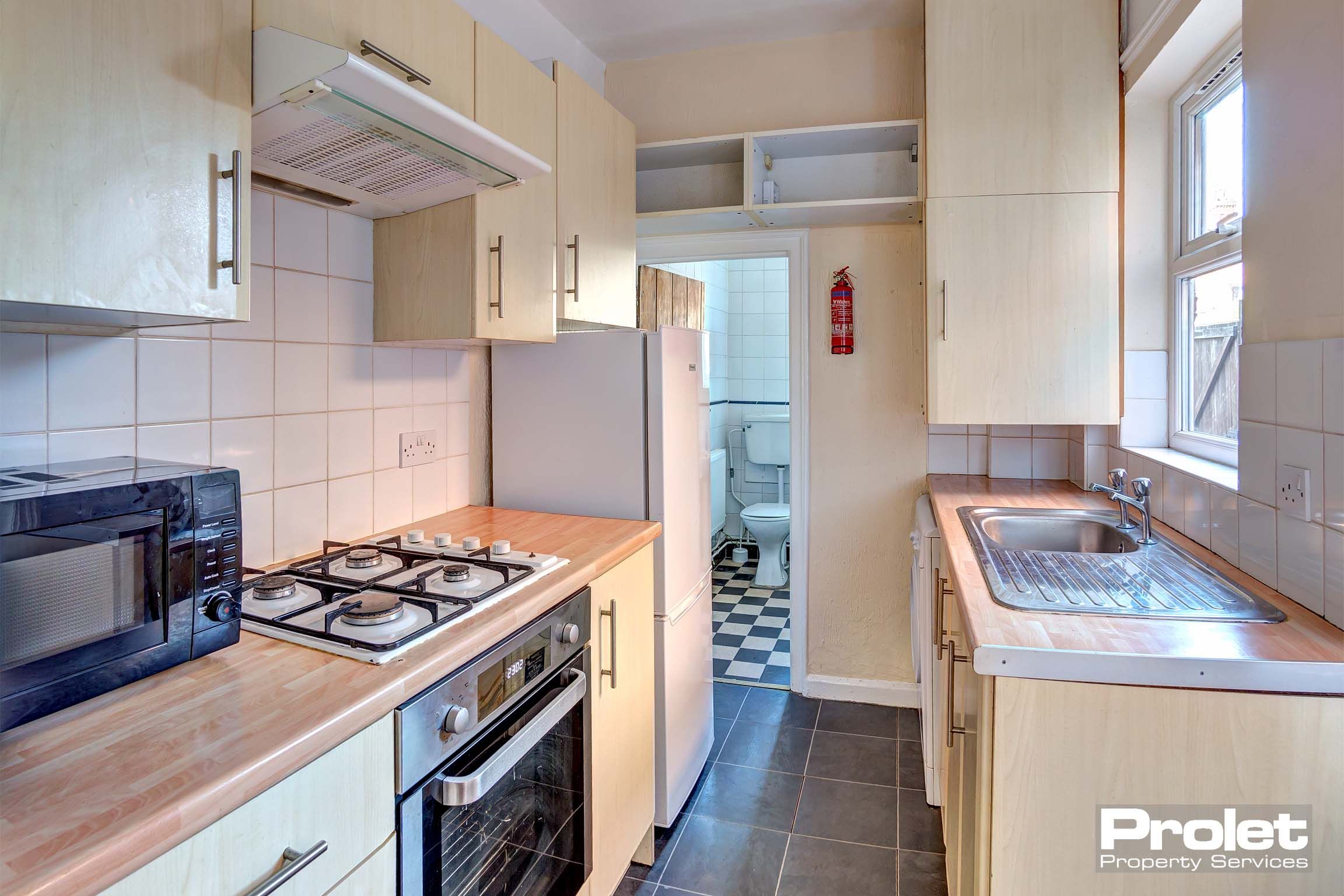 Galley kitchen with wood effect cabinets, and worktops, and white goods