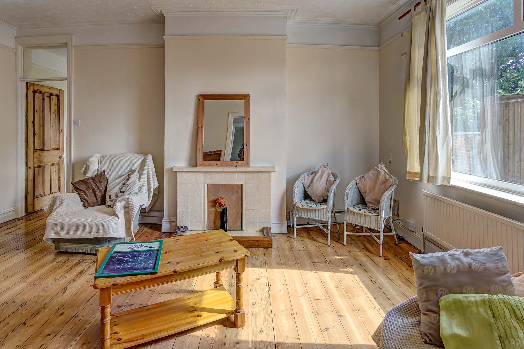 Spacious living room with wooden floors, and arm chairs.