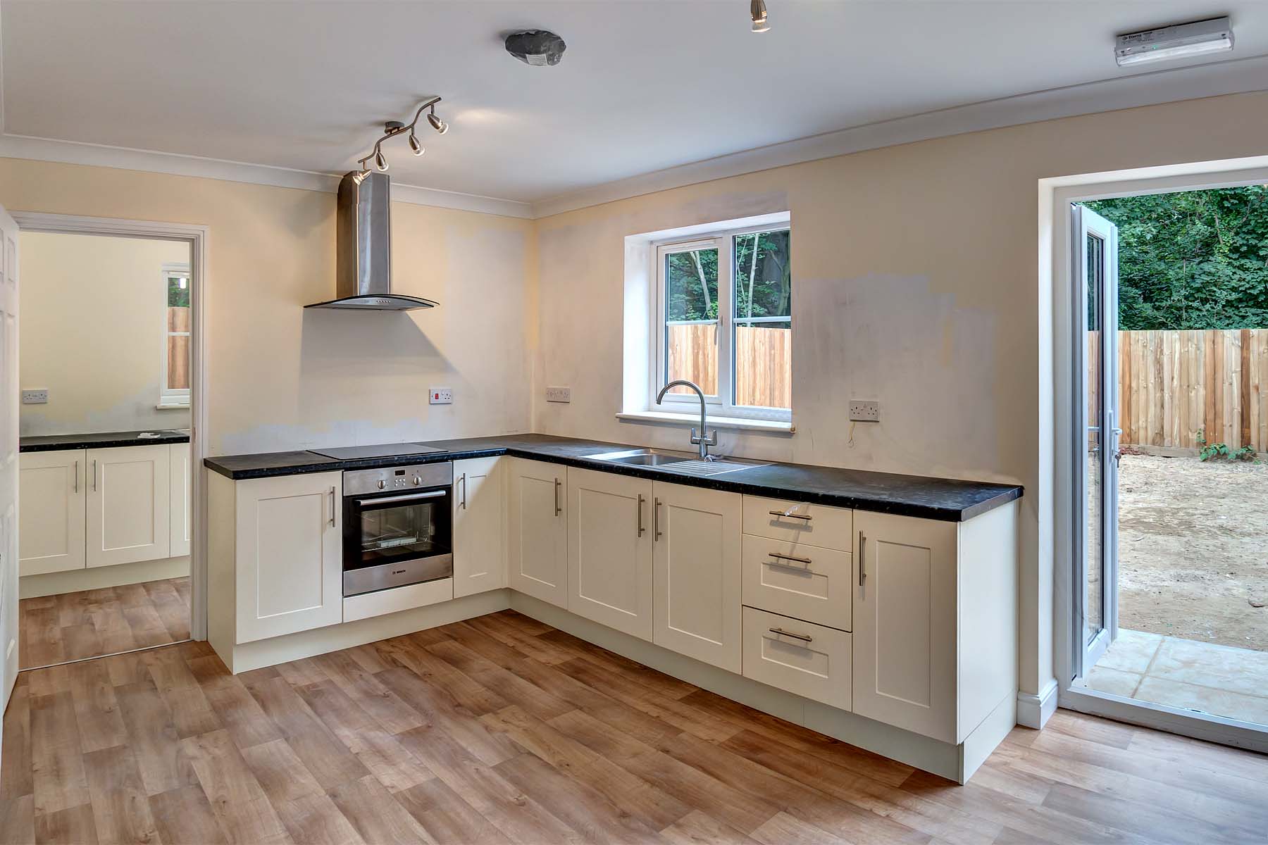 Large modern kitchen with white cupboards and black worktop.