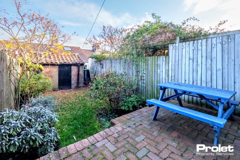 Enclosed rear garden with lawn and brick patio and picnic bench