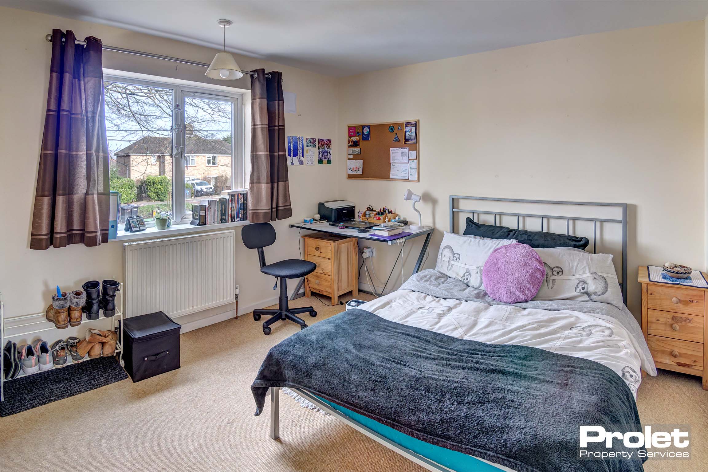 Double bedroom with metal bed frame, a desk and chair and a wooden bedside table.