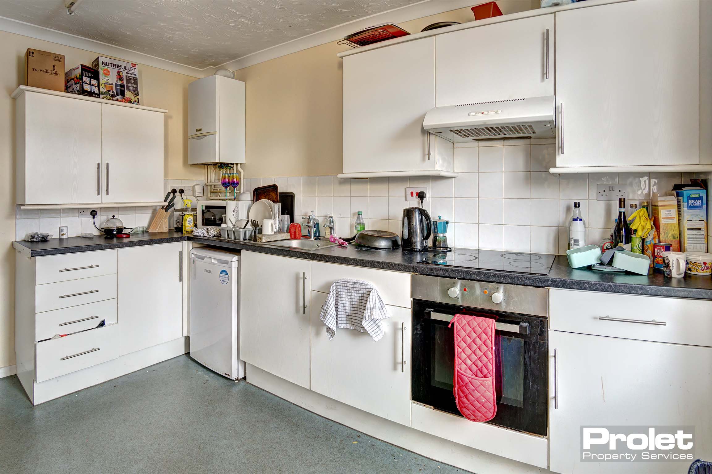 White fitted kitchen with magnolia walls and black worktop.