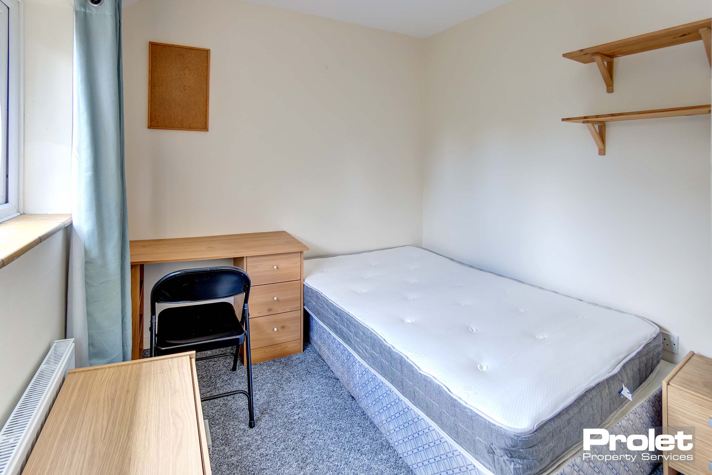 Double bedroom with bed, wooden desk, and black chair