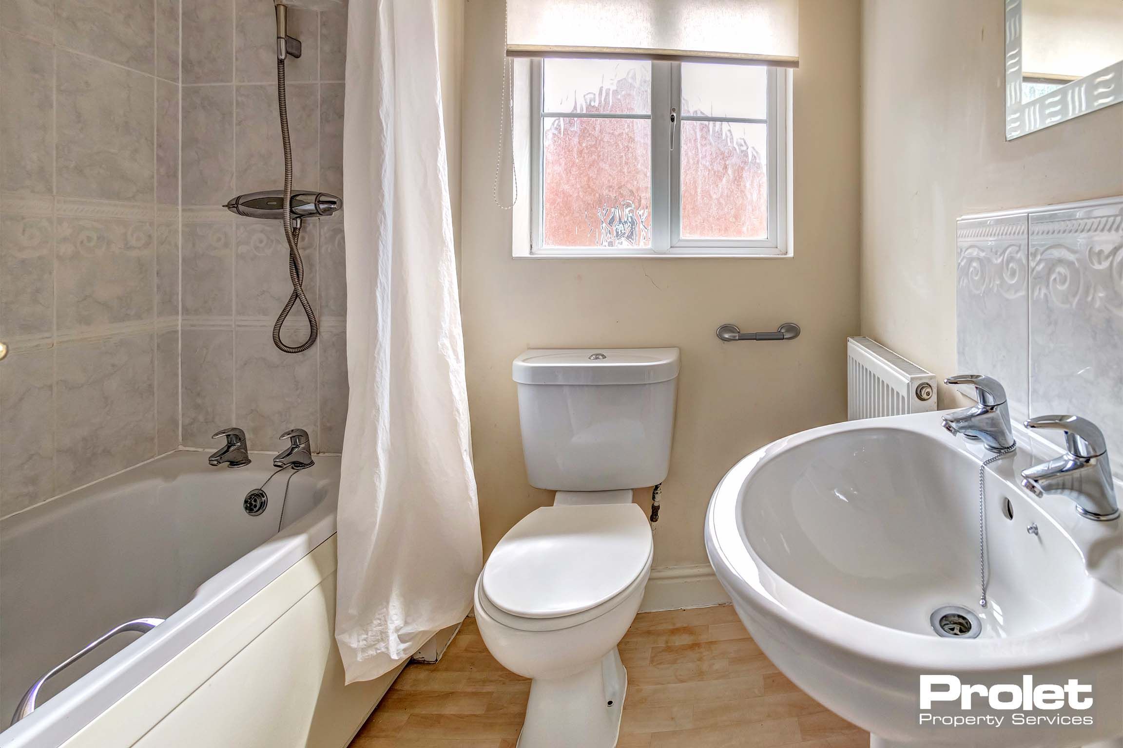 Bathroom with toilet, sink, and shower over bath