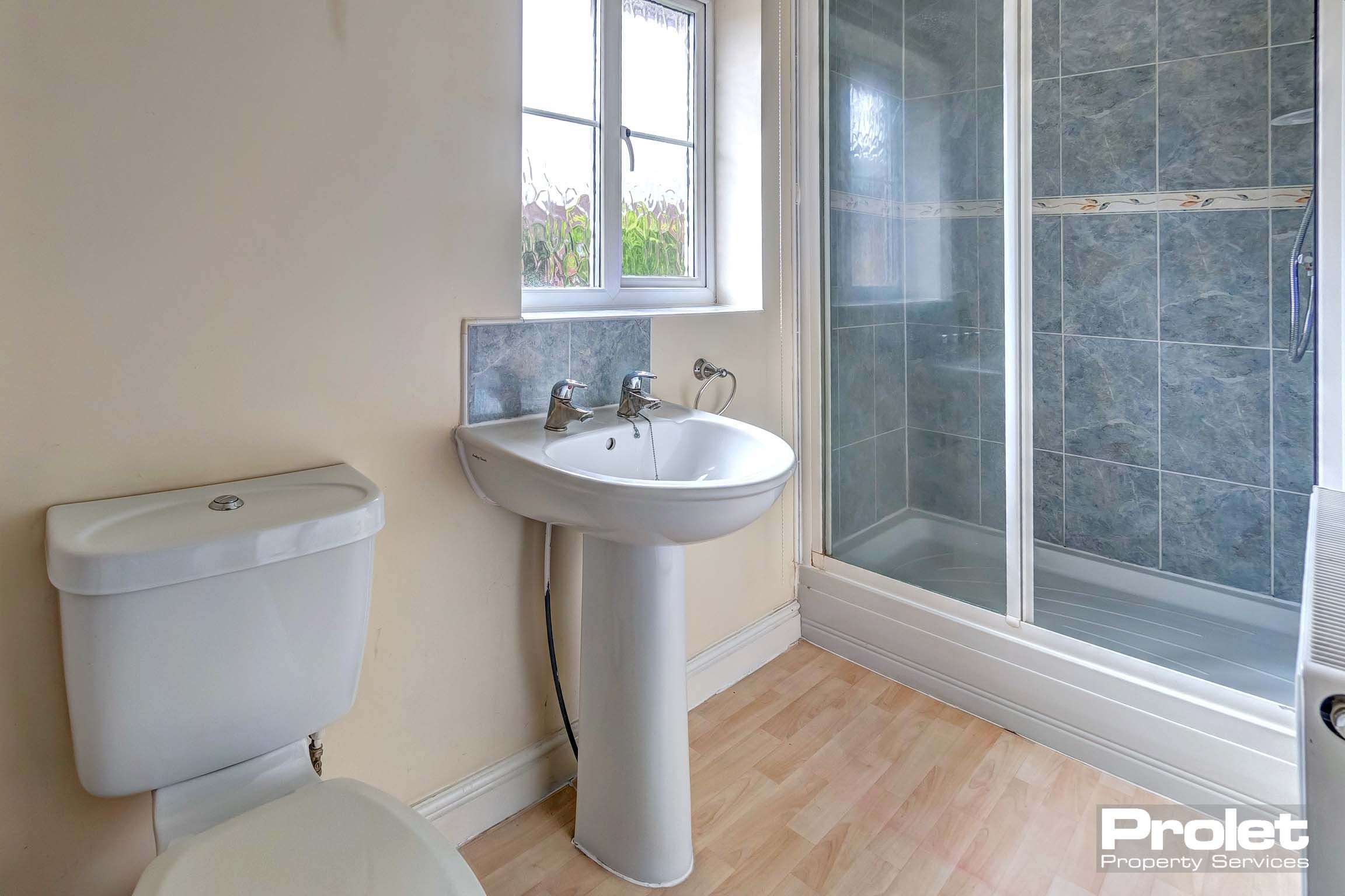 Bathroom with toilet, sink, and shower cubicle