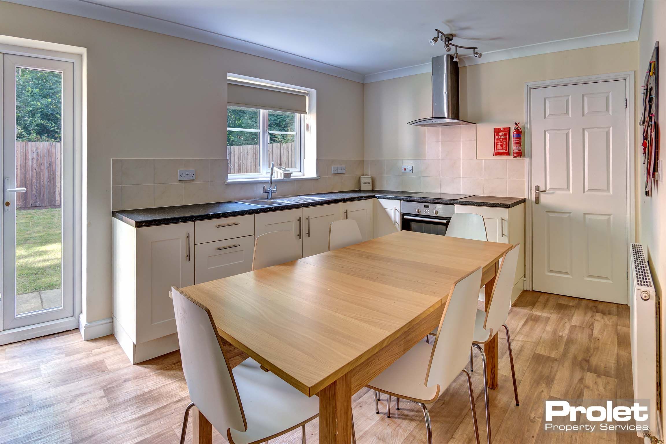 Modern kitchen with white cupboards, black work top and dining set