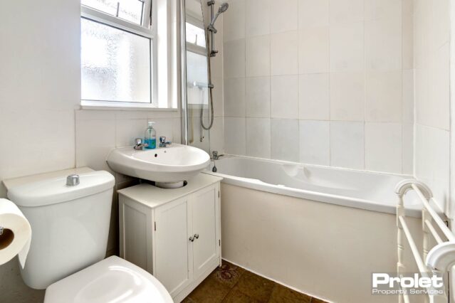 Bathroom with shower over bath, toilet, and sink