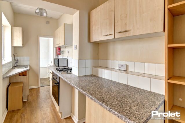 Kitchen with wood effect cabinets and black worktop