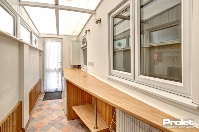 Utility room with shelving, leading to garden