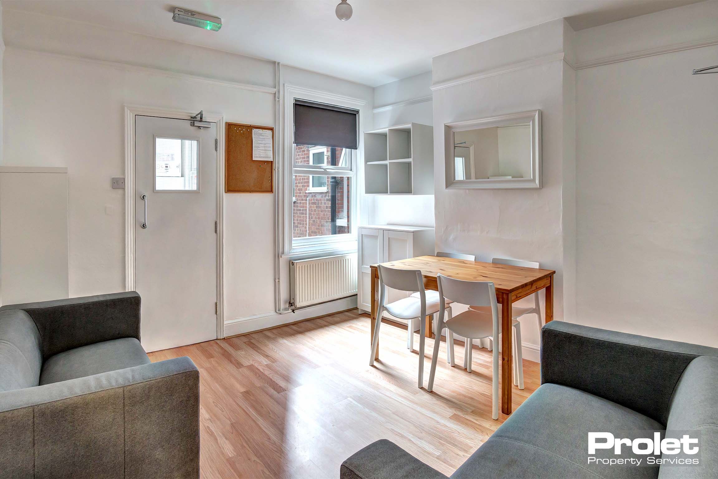 Lounge and dining area with two grey fabric sofas and a wooden dining chairs with white chairs.