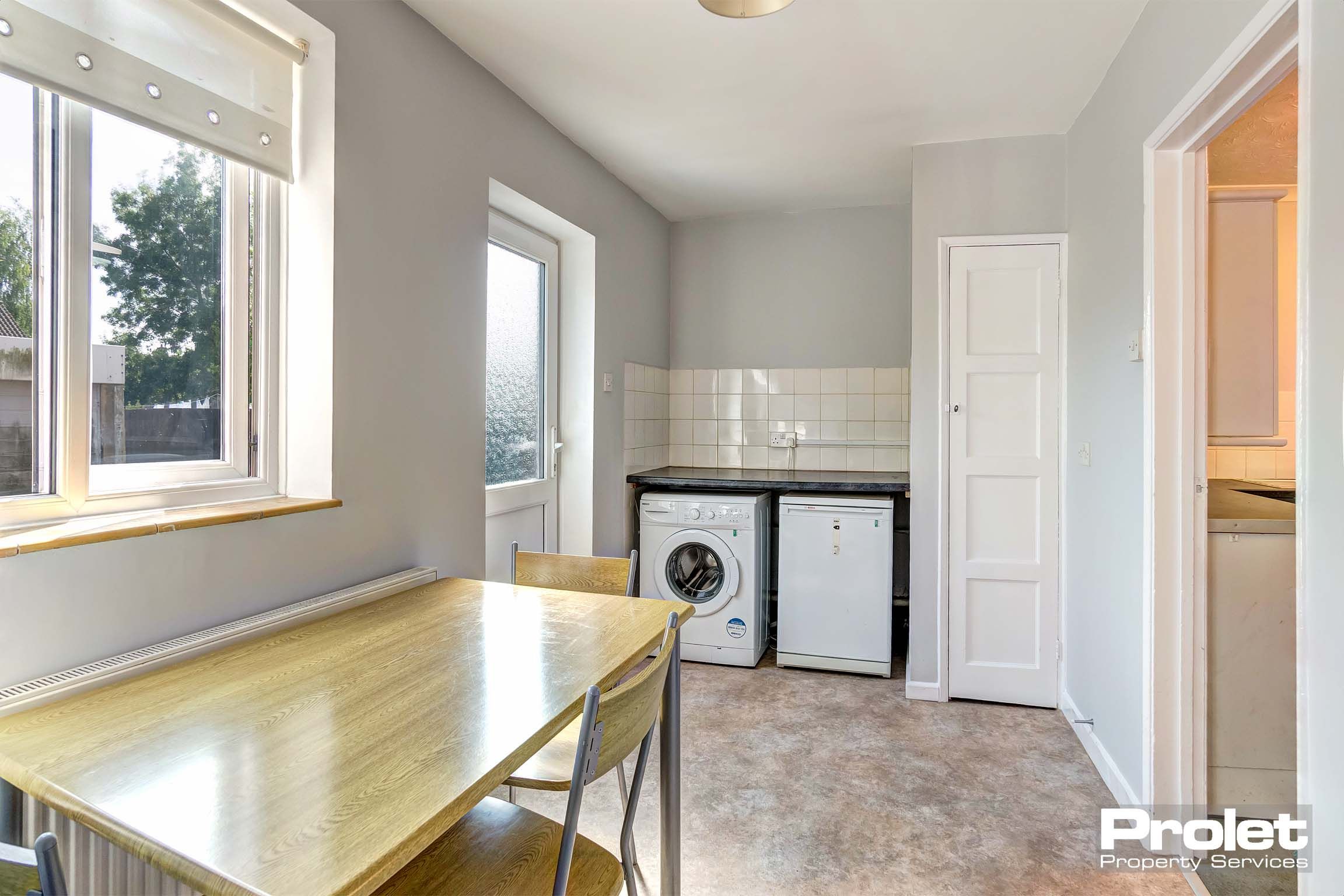 Dining area with wooden dining table and chairs and under the counter fridge/freezer and washing machine.