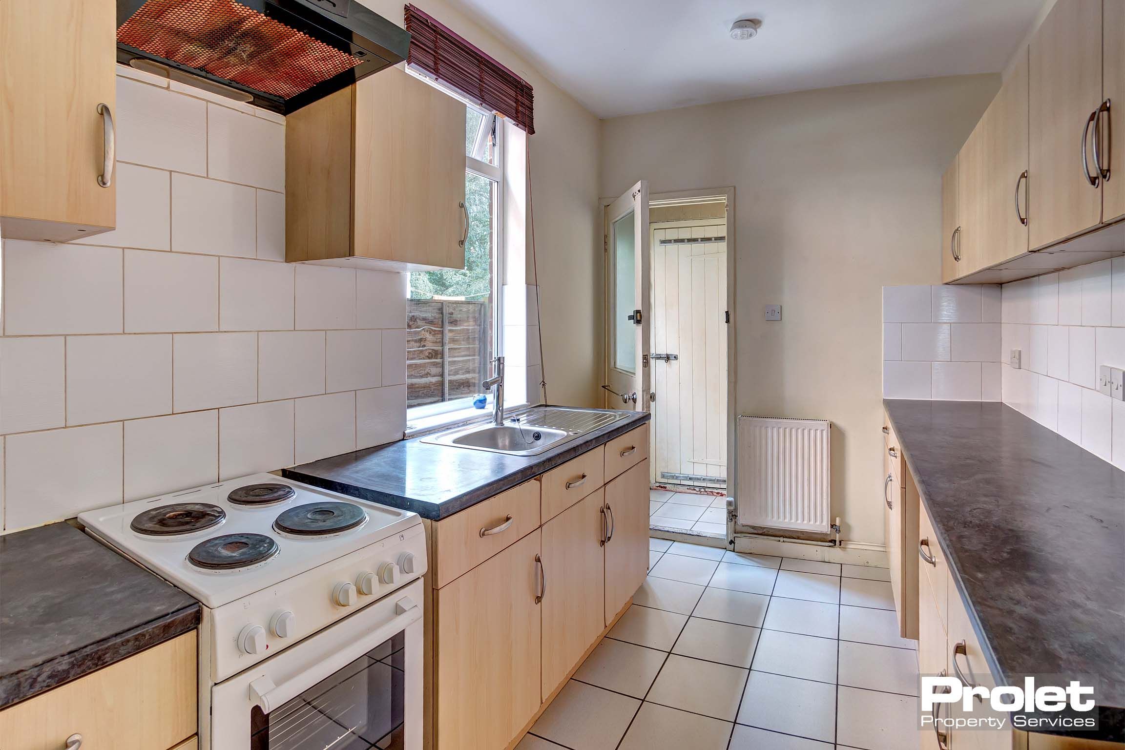 Kitchen with wooden cabinets, large appliances, and tiled floor