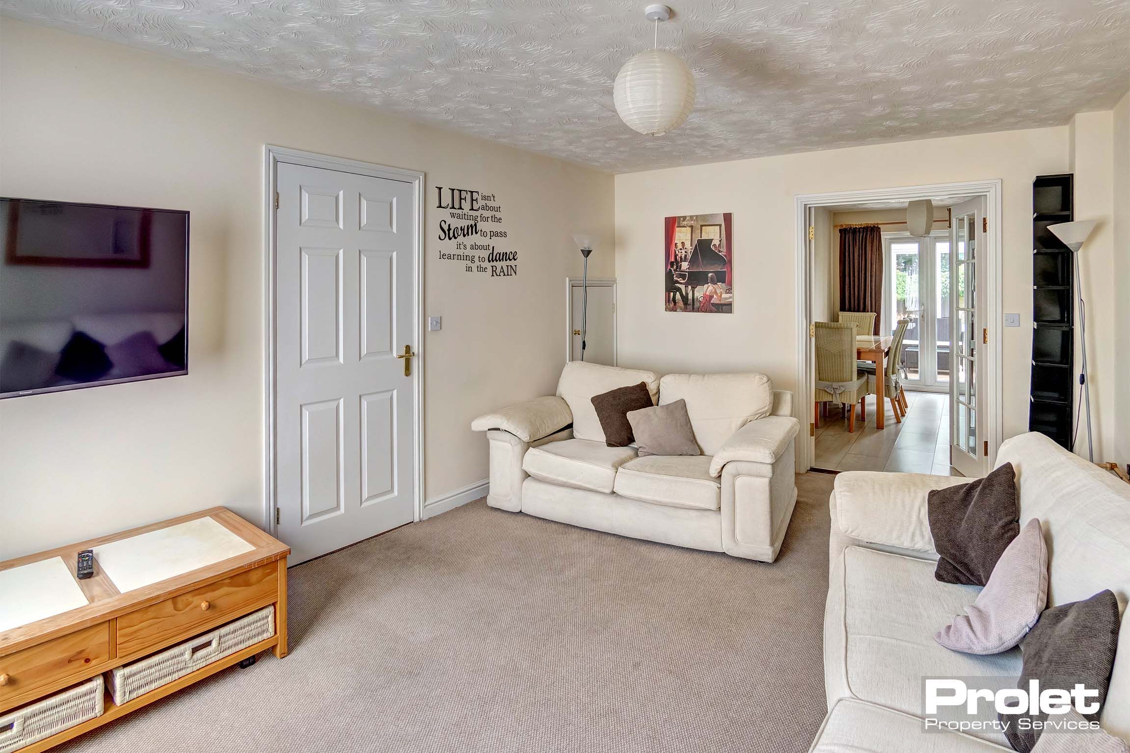 Large lounge area with two white leather sofas, a brown carpet and magnolia walls.