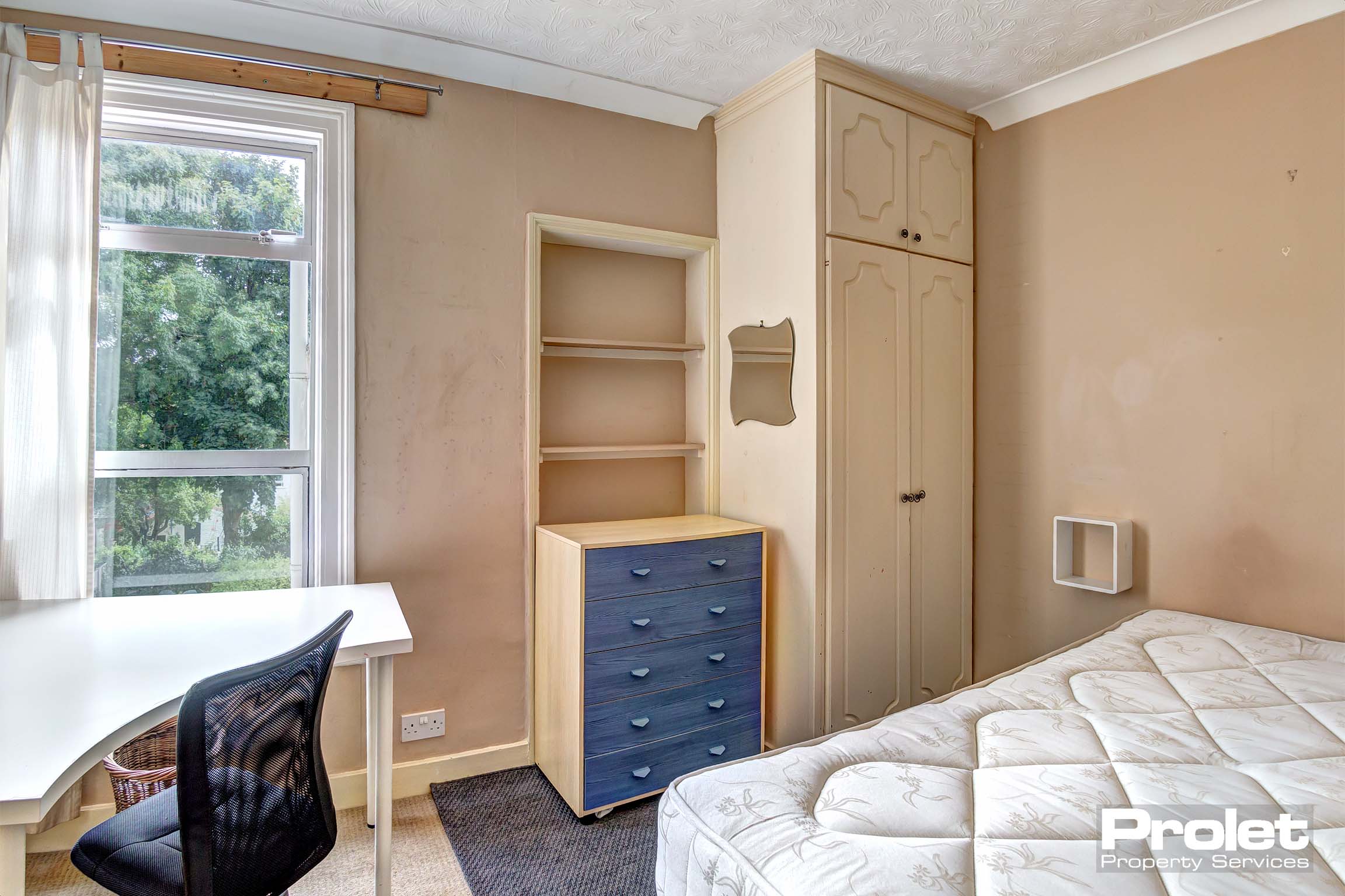 Bedroom with corner desk, wooden wardrobe, chest of drawers and a bed frame.